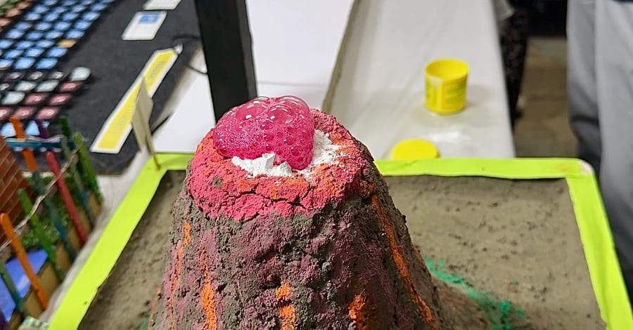 A student-built model volcano erupting with pink foam